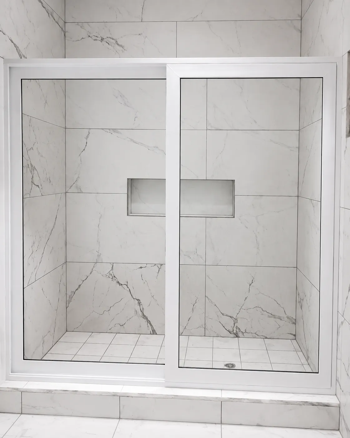 Mampara corrediza blanca instalada en un baño revestido