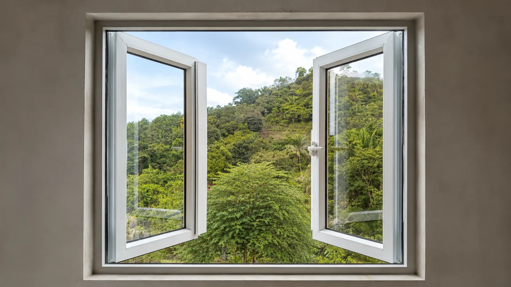 Ventana blanca abatible abierta hacia un paisaje verde